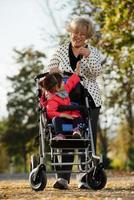 grand-mère et sa petite-fille autiste profitant de vacances ensemble à l'extérieur, allongées sur l'herbe verte sur une couverture et souriant à la caméra. loisirs vie familiale, bonheur et moments. photo