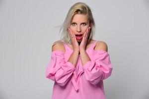 portrait d'une belle jeune femme en chemise rose mignonne et jeans bleus posant en studio. concept de beauté, émotions, expression faciale, style de vie, mode, culture des jeunes photo