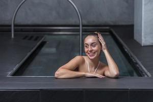 femme gaie touchant les cheveux dans la piscine photo