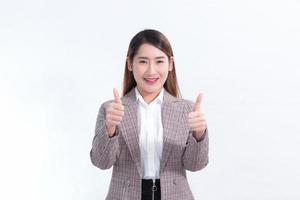 belle femme d'affaires cheveux longs asiatique en costume, souriant et pouce en l'air et présentant quelque chose sur fond blanc. photo