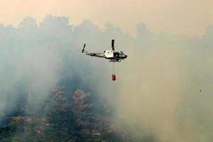 un hélicoptère éteint un feu de forêt dans les montagnes du nord d'israël. photo