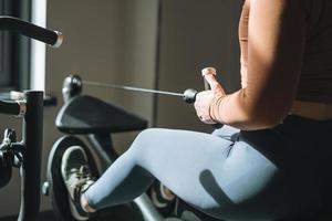 jeune femme brune de remise en forme s'entraînant pour l'équipement des muscles des mains et des jambes à la salle de sport photo