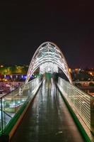 le pont de la paix à tbilissi, un pont piétonnier sur la rivière mtkvari à tbilissi, géorgie illuminée la nuit. photo
