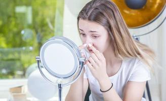 vérifier la peau problématique du visage à la maison. jeune adolescent avec des problèmes de soi regardant dans le miroir. fille avec une faible estime de soi vérifiant sa peau dans un miroir photo