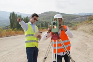 l'ingénieur géomètre mesure le niveau sur le chantier de construction. les géomètres assurent des mesures précises avant d'entreprendre de grands projets de construction. photo