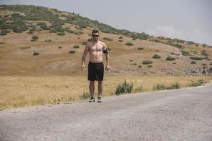 coureur de jeune homme courant sur une route de montagne. séance d'entraînement de jogger dans une chaussure de fitness. mode de vie sain et concept sportif. flou de mouvement et mise au point sélective. photo