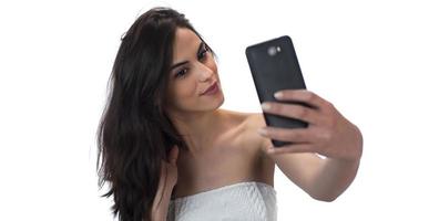 image d'une belle femme brune riant tout en prenant une photo de selfie sur un téléphone portable isolé sur fond blanc