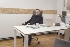 jeune homme d'affaires travaillant à la maison avec un ordinateur portable et des papiers sur le bureau photo