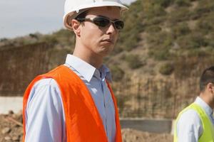 l'ingénieur géomètre mesure le niveau sur le chantier de construction. les géomètres assurent des mesures précises avant d'entreprendre de grands projets de construction. photo