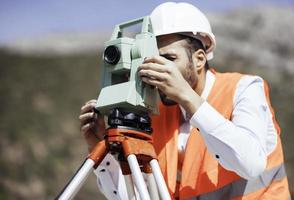 l'ingénieur géomètre mesure le niveau sur le chantier de construction. les géomètres assurent des mesures précises avant d'entreprendre de grands projets de construction. photo