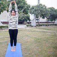 jeune femme indienne pratiquant le yoga en plein air dans un parc. belle fille pratique la pose de yoga de base. calme et détente, bonheur féminin. exercice de yoga de base en plein air photo