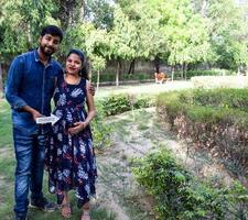 couple indien posant pour une séance photo de maternité. le couple pose dans une pelouse avec de l'herbe verte et la femme étale sa bosse de bébé dans le jardin de lodhi à new delhi, inde