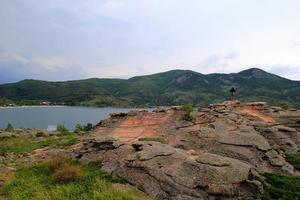 voyage au kazakhstan, parc national de bayanaul. le jeune homme regarde la vue avec un lac et des montagnes. photo