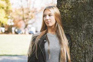 adolescente rêveuse se penchant contre l'arbre photo