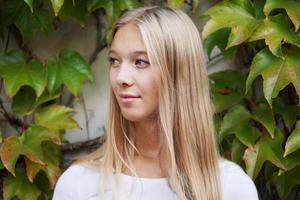 cool jeune femme debout dehors devant un mur recouvert de lierre photo