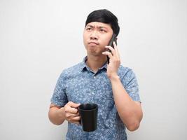 chemise bleue homme parlant avec un téléphone portable et tenant une tasse de café sentir la souche photo