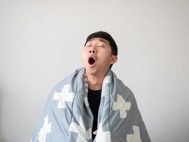 l'homme se réveille avec une couverture couvre son corps et se sent somnolent et bâille ferme l'œil sur blanc isolé photo