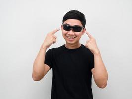 homme asiatique gai pointant du doigt des lunettes de soleil sur son visage photo