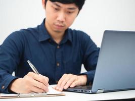 homme écrivant un document sur la table et utilisant un ordinateur portable travaillant à domicile concept photo