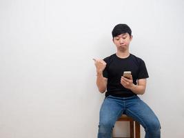 homme asiatique regardant un smartphone dans la main et pointant du doigt l'espace de copie sur fond blanc photo
