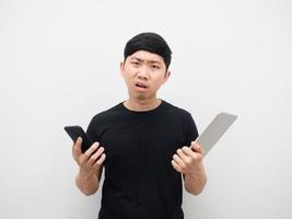 homme asiatique tenant une tablette et un téléphone portable émotion sérieuse et souche photo