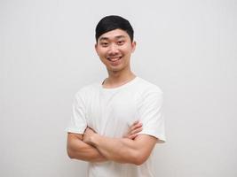 jeune homme asiatique bras croisés chemise blanche avec un sourire heureux sur son visage se sentir confiant sur l'isolat blanc photo