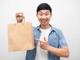 Cheerful man smiling point doigt au sac à provisions à la main photo