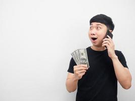 homme asiatique parlant avec un téléphone portable tenant de l'argent dans sa main se sentant excité photo