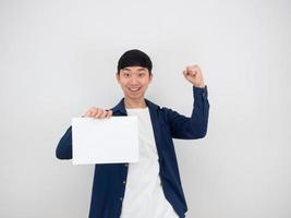 bel homme heureux et joyeux poing vers le haut et tenant du papier vierge à la main avec sourire regarder la caméra sur blanc isolé photo