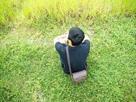 homme assis sur l'herbe avec vue naturelle sur la montagne et le lac.homme assis sur l'herbe verte sur la montagne et regardant naturel et lac photo