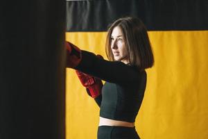 jeune femme brune en vêtements noirs engagé dans un entraînement de boxe fitness club gym photo