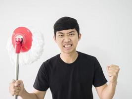 homme asiatique chemise noire se sentir en colère face au poing tenant une vadrouille à la main sur fond blanc isoler la moitié du corps de la récolte photo