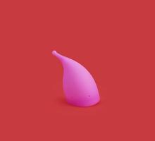 coupe menstruelle en silicone réutilisable rose isolée sur fond rouge. photo