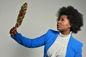 jolie femme afro-américaine avec des accessoires à la mode et une coiffure afro regardant la caméra sur fond gris photo