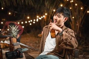 les jeunes hommes asiatiques tenant une bouteille de bière profitent de la soirée photo