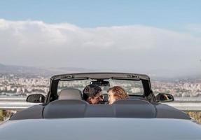 amis s'amusant lors d'un voyage en voiture autour du monde. couple amoureux avec les bras levés sur une voiture décapotable. photo