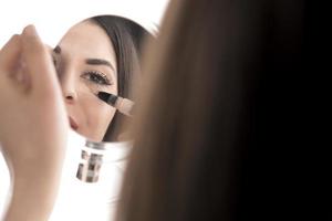 portrait d'une jeune femme appliquant un maquillage liquide sur son visage. isolé sur fond blanc photo