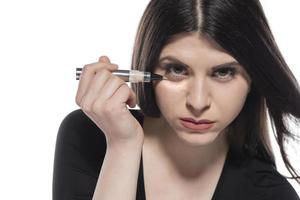 portrait d'une jeune femme appliquant un maquillage liquide sur son visage. isolé sur fond blanc photo