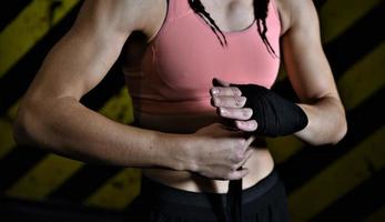 gros plan d'une femme faisant des bandages de boxe dans une cage de combat photo