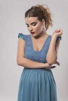 Belle femme en robe bleue qui pose en studio sur fond gris photo