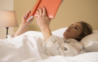 belle jeune femme lisant un livre avant d'aller dormir. photo