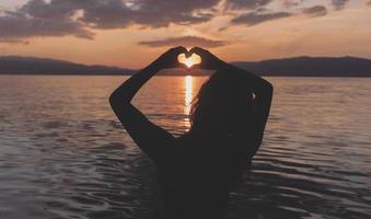Geste de la main silhouette sentiment d'amour pendant le coucher du soleil photo