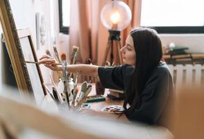 jeune femme artiste adolescente étudiante aux cheveux longs noirs dans des tirages décontractés photo au studio d'art