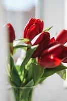 beau bouquet de tulipes rouges dans un vase sur un rebord de fenêtre à la maison, arrière-plan naturel photo