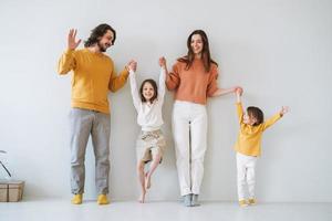 jeune famille heureuse avec deux enfants filles sur fond de mur gris photo