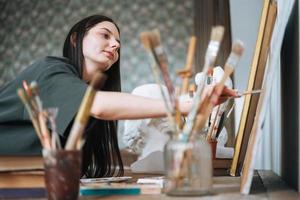 jeune femme artiste adolescente étudiante aux cheveux longs noirs dans des tirages décontractés photo au studio d'art