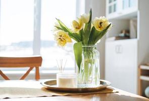 beau bouquet de tulipes jaunes dans un vase sur la table du dîner dans l'intérieur lumineux de la cuisine blanche à la maison photo