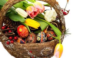 oeufs de pâques dans un panier en bois. tulipes de fleurs de printemps. panier avec des oeufs de pâques isolé sur fond blanc photo