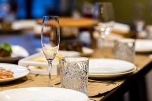 verre vide situé dans le restaurant. mariage, décoration, fête, concept de vacances - table romantique avec nappe blanche, assiettes, verres en cristal photo