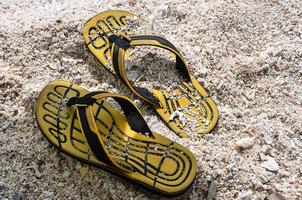 chaussons en caoutchouc jaune sur la plage de sable photo